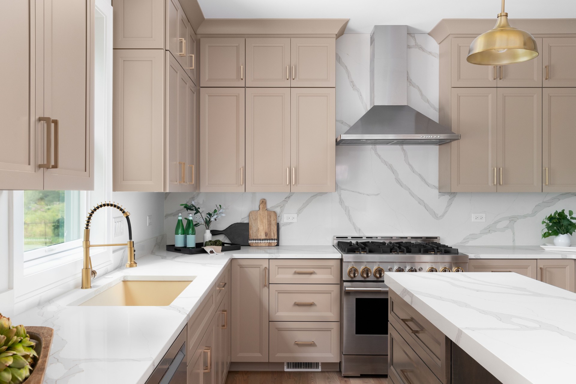 A kitchen with brown cabinets, white countertops, and gold fixtures.